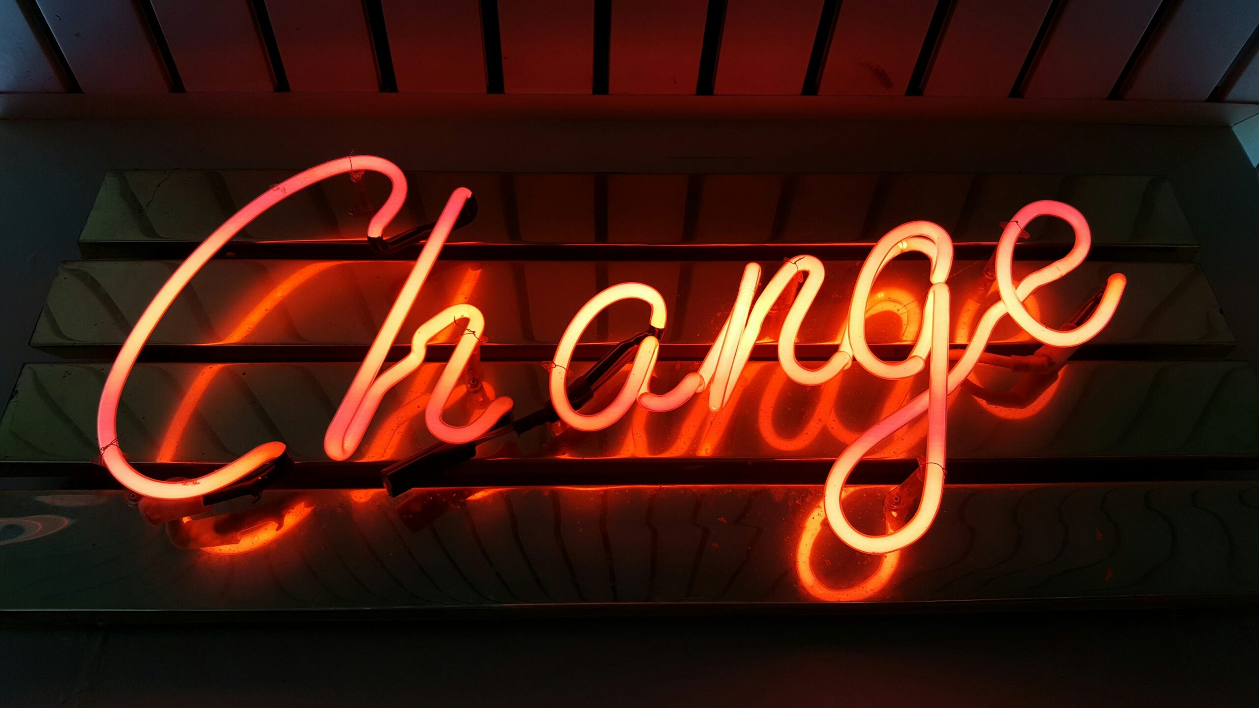 An orange neon sign spells out 'change' on a dark background